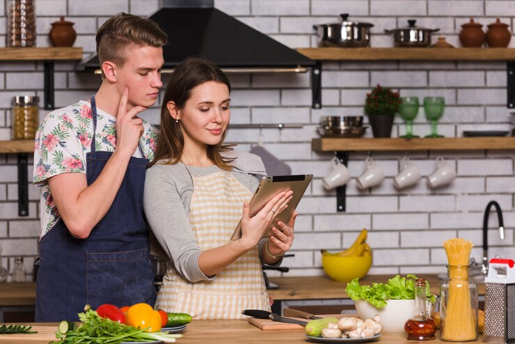 Foto gratuito pareja joven viendo receta en tableta en cocina