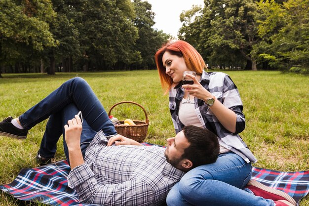 Pareja joven viendo el video en el teléfono móvil en picnic