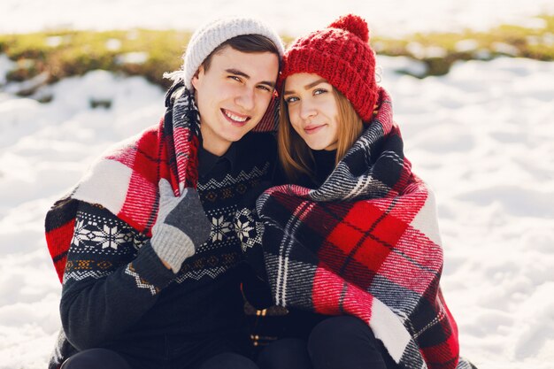 Pareja joven vistiendo una manta en un campo cubierto de nieve