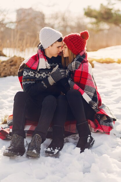 Pareja joven vistiendo una manta en un campo cubierto de nieve