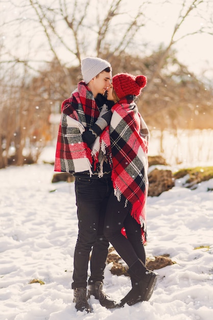 Pareja joven vistiendo una manta en un campo cubierto de nieve