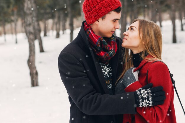 Pareja joven vistiendo una manta en un campo cubierto de nieve