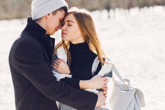 Pareja joven vistiendo una manta en un campo cubierto de nieve