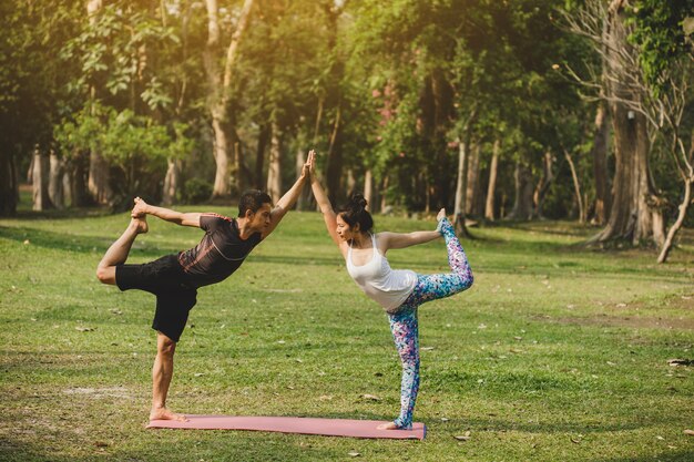 Pareja de jóvenes sanos haciendo yoga en el parque