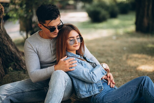 Pareja de jóvenes sentados en el césped en el parque