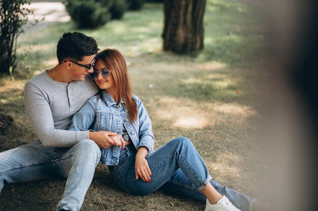 Pareja de jóvenes sentados en el césped en el parque