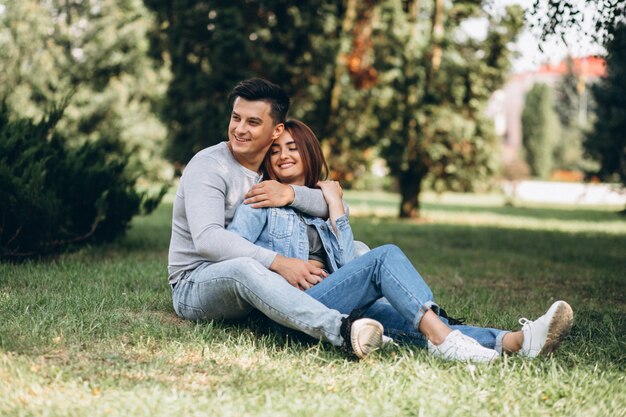 Pareja de jóvenes sentados en el césped en el parque