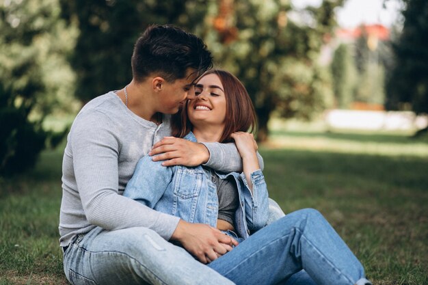 Pareja de jóvenes sentados en el césped en el parque