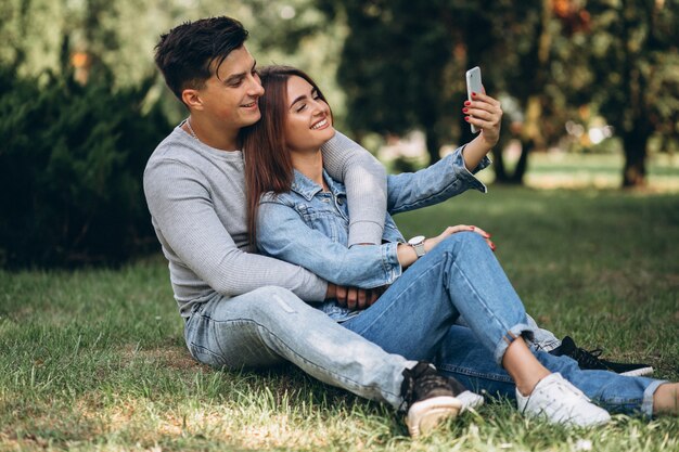 Pareja de jóvenes sentados en el césped en el parque