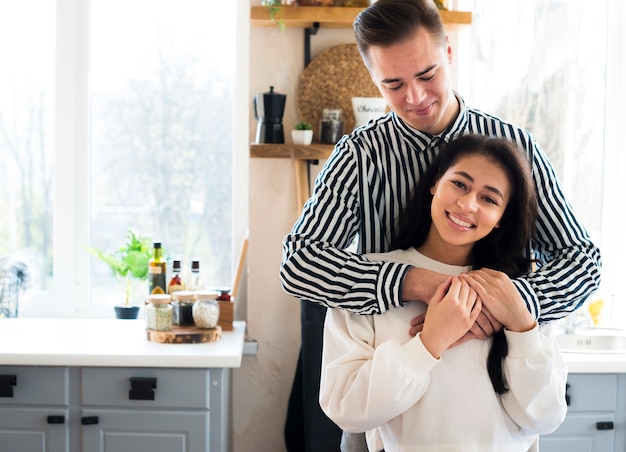 Pareja de jóvenes sentados en la cocina y abrazos