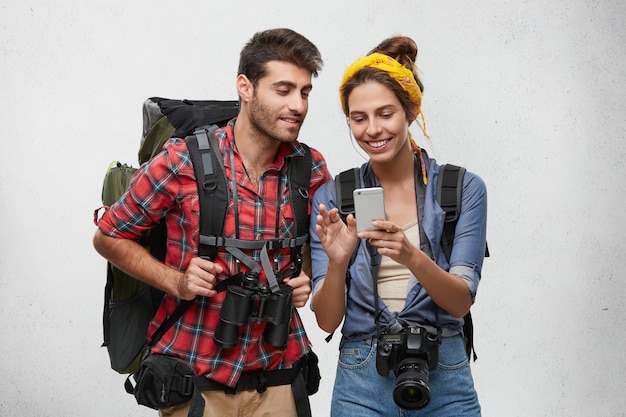 Foto gratuita pareja de jóvenes turistas con equipo