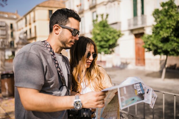 Pareja de jóvenes turistas con estilo mirando el mapa