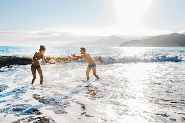 Pareja jugando en el agua en la playa