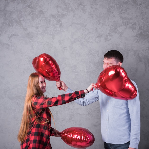 Pareja jugando con globos de corazón