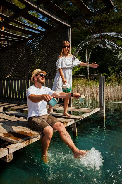 Pareja jugando y hombre sentado con los pies en el agua