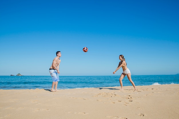 Pareja jugando a la pelota en la playa