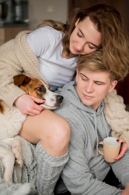 Foto gratuita pareja jugando con perro en casa