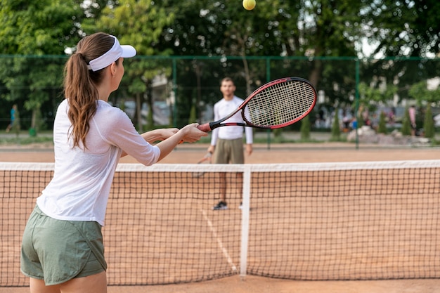 Pareja jugando tenis en la cancha