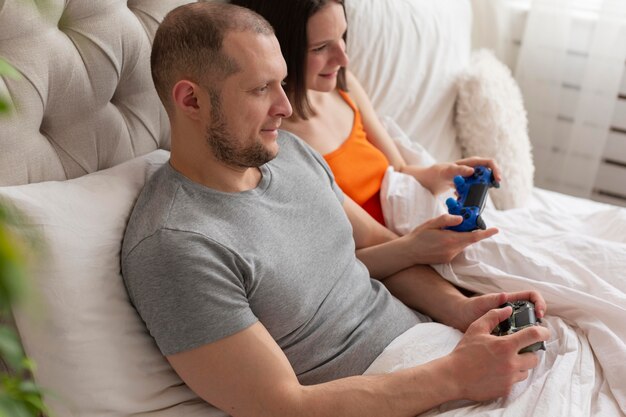 Pareja jugando videojuegos en la cama