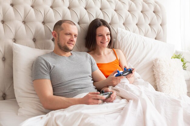 Pareja jugando videojuegos en la cama