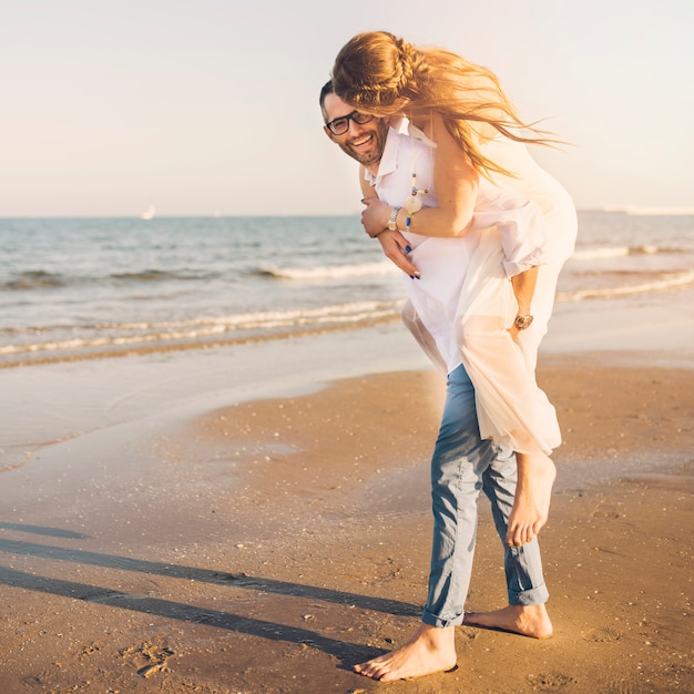 Foto gratuita pareja juguetona en la playa del océano disfrutando de sus vacaciones de verano