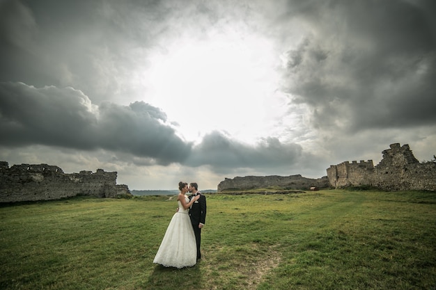 Pareja junta en un atardecer entre nubes en un campo