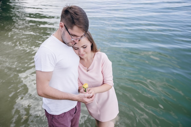 Pareja junta en el mar sujetando una flor amarilla