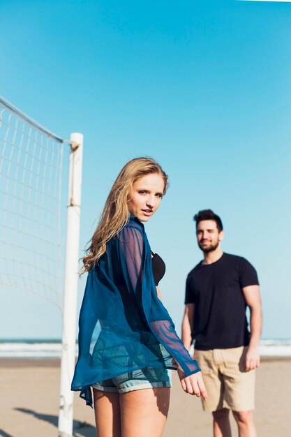 Pareja junto a la red de voleibol mirando a cámara