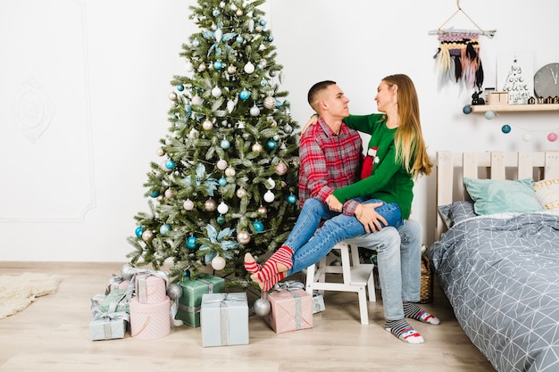 Pareja juntos al lado de árbol de navidad