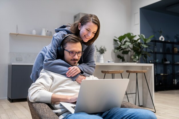 Pareja juntos en la cocina trabajando en equipo portátil