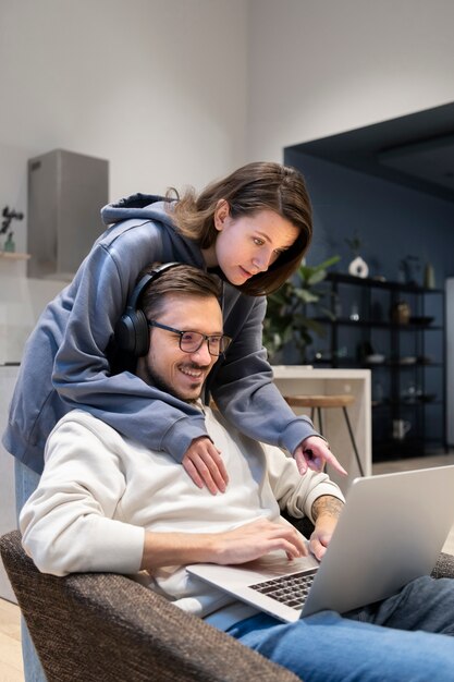 Pareja juntos en la cocina trabajando en equipo portátil