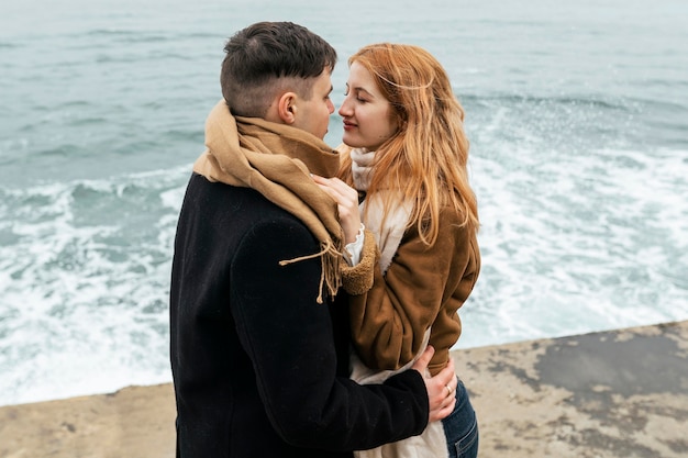 Pareja por el lago durante el invierno abrazado