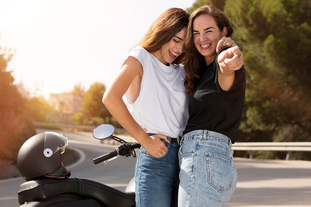 Pareja de lesbianas abrazando cerca de la motocicleta durante un viaje por carretera