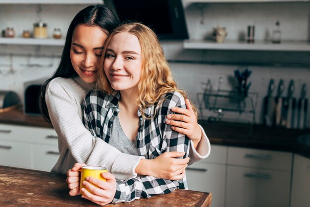 Pareja de lesbianas abrazándose en la cocina