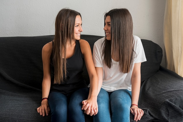 Pareja de lesbianas alegre sentado en el sofá