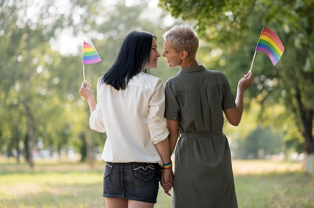 Pareja de lesbianas caminando y sosteniendo la bandera