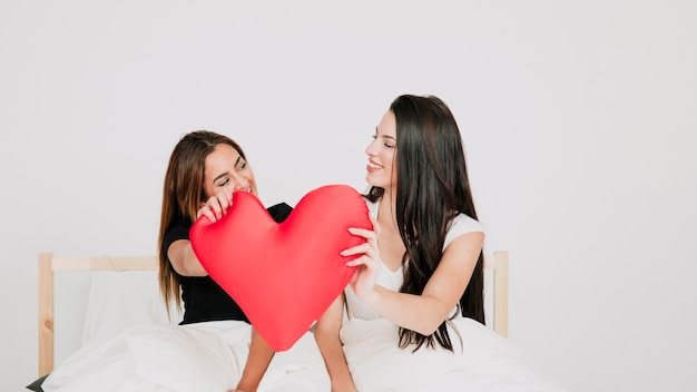 Pareja de lesbianas con corazón en la cama