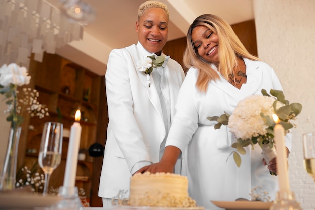 Foto gratuita pareja de lesbianas cortando el pastel en su boda