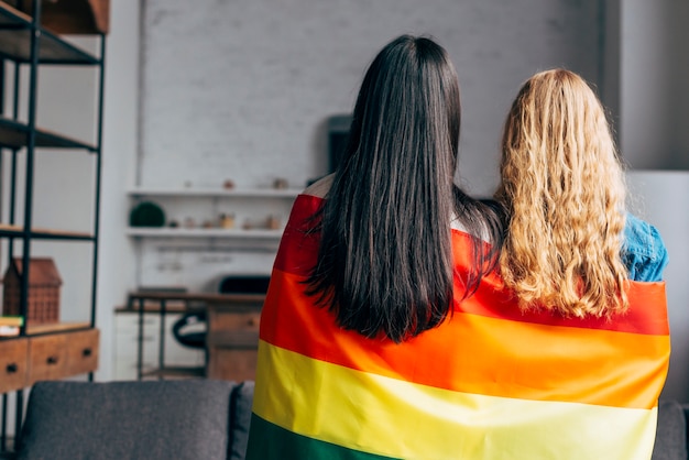 Foto gratuita pareja de lesbianas envuelta en bandera de arcoiris