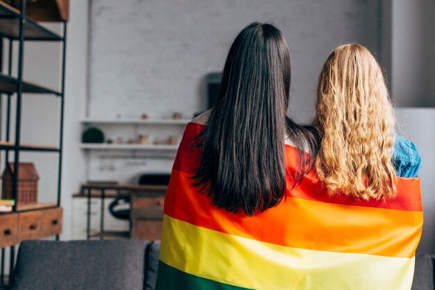 Pareja de lesbianas envuelta en bandera de arcoiris