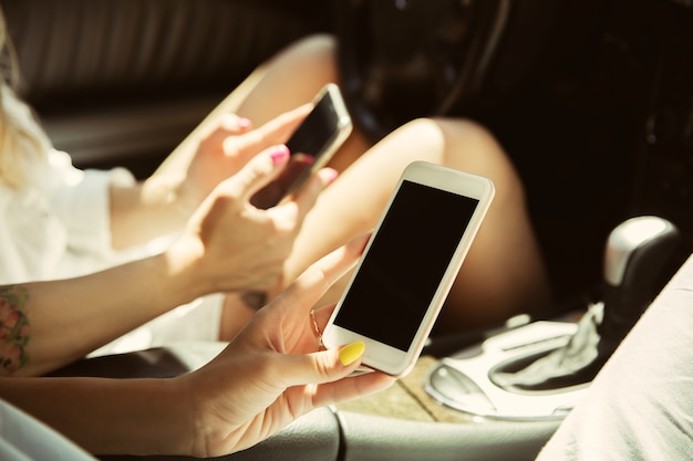 Pareja de lesbianas jóvenes preparándose para el viaje de vacaciones en el coche en un día soleado. Mujeres sentadas y listas para ir al mar, a la orilla del río o al océano. Concepto de relación, amor, verano, fin de semana, luna de miel.