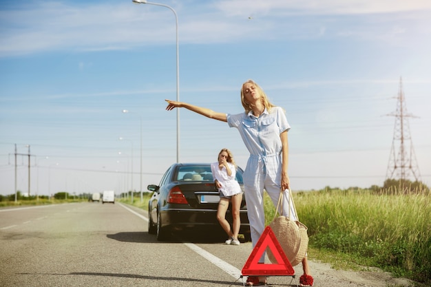 Foto gratuita pareja de lesbianas jóvenes que van de viaje de vacaciones en el coche en un día soleado