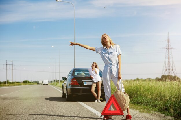 Pareja de lesbianas jóvenes que van de viaje de vacaciones en el coche en un día soleado