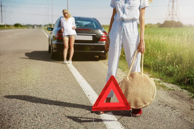 Pareja de lesbianas jóvenes que van de viaje de vacaciones en el coche en un día soleado