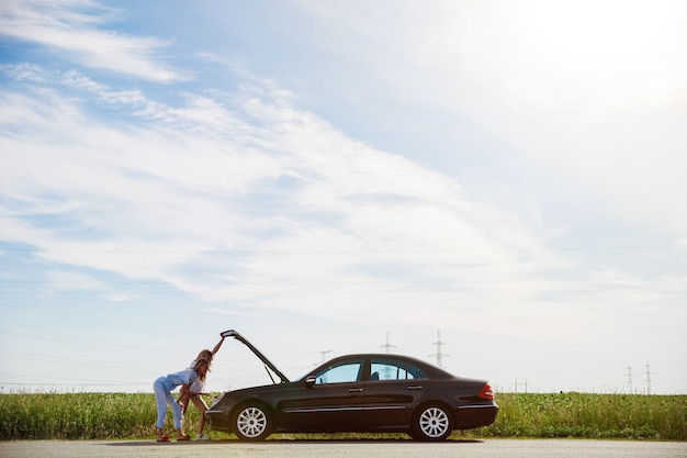 Pareja de lesbianas jóvenes que van de viaje de vacaciones en el coche en un día soleado