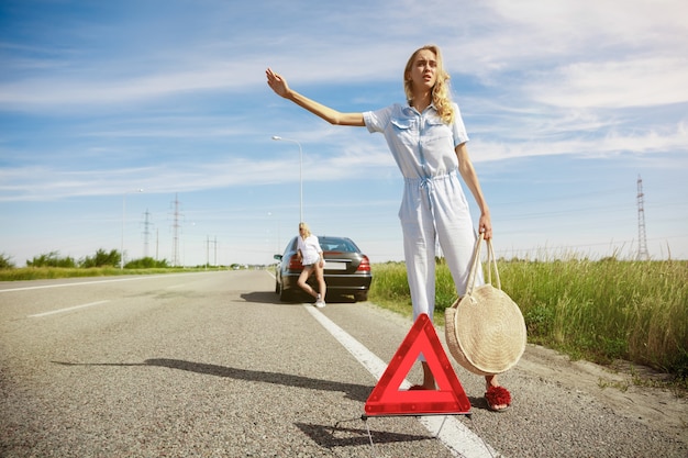 Pareja de lesbianas jóvenes que van de viaje de vacaciones en el coche en un día soleado