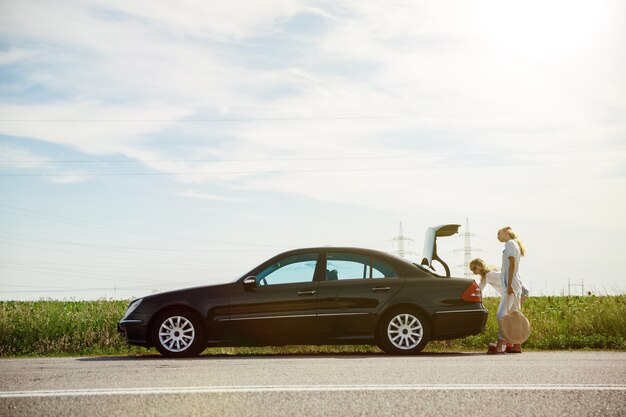 Pareja de lesbianas jóvenes que van de viaje de vacaciones en el coche en un día soleado