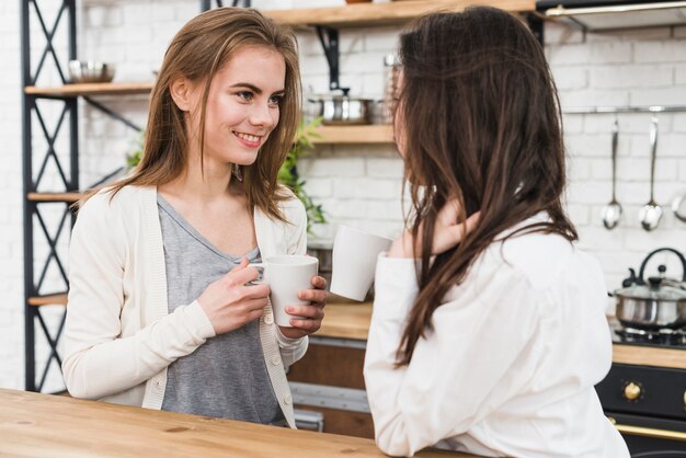 Pareja de lesbianas jóvenes sosteniendo una taza de café en la mano mirando el uno al otro