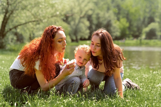 Foto gratuita pareja de lesbianas pasar tiempo con su hijo en el parque