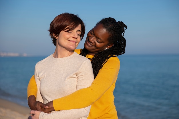 Pareja de lesbianas de tiro medio en la playa